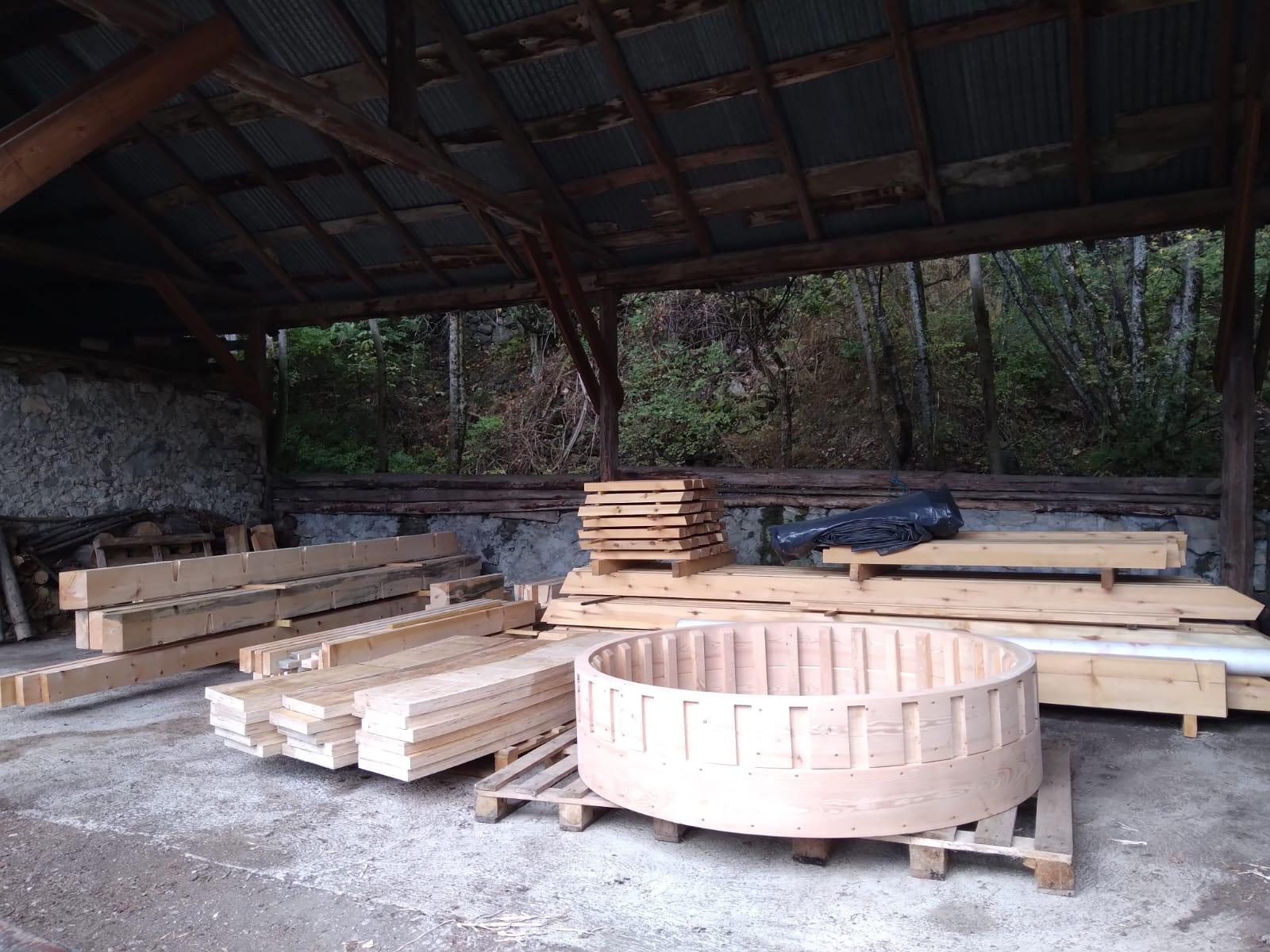Atelier de charpentier avec poutres, planches et pièces rondes en bois préparées pour l'assemblage